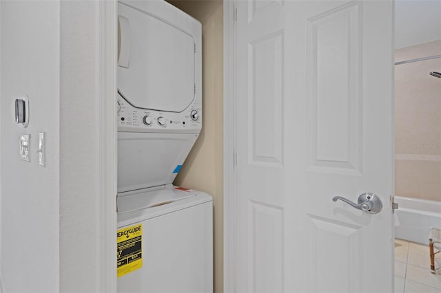 washroom featuring stacked washer and clothes dryer and light tile patterned flooring