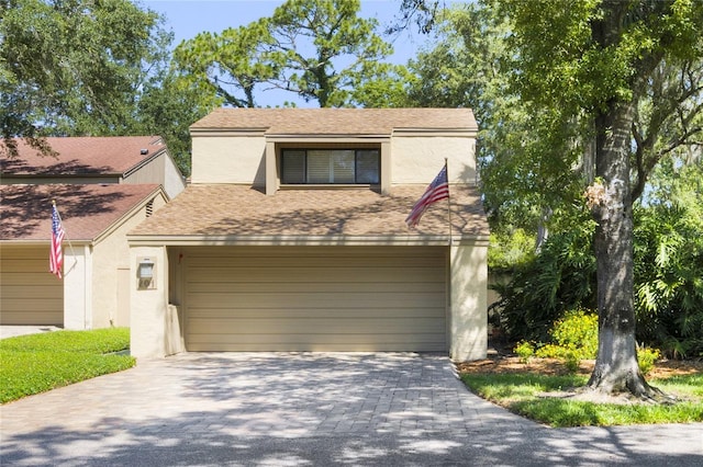 view of front of property with a garage, decorative driveway, roof with shingles, and stucco siding