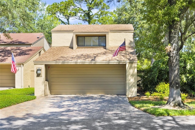 view of front of house featuring decorative driveway, roof with shingles, and stucco siding