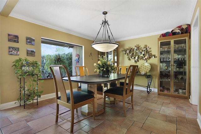 dining area with stone finish flooring, ornamental molding, and baseboards