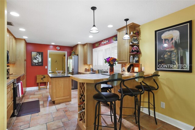 kitchen with appliances with stainless steel finishes, a kitchen bar, pendant lighting, and kitchen peninsula