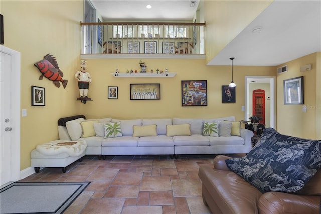 living area with stone finish floor, visible vents, and a high ceiling