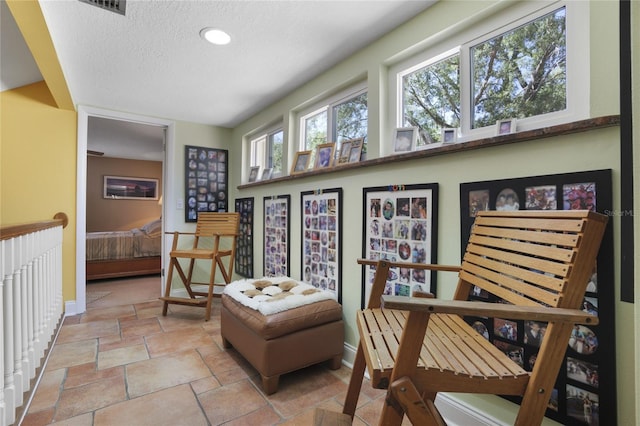 living area featuring stone tile floors, baseboards, and a textured ceiling