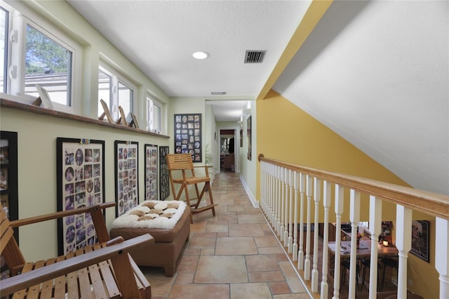 corridor with lofted ceiling, recessed lighting, visible vents, baseboards, and stone finish flooring