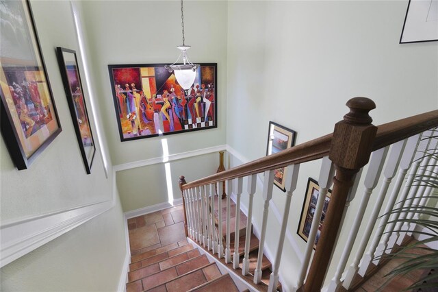 stairs featuring baseboards and stone tile floors