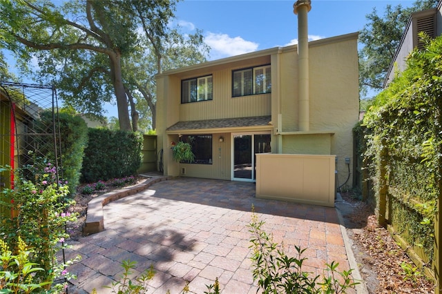 rear view of house featuring a shingled roof, a patio area, and a fenced backyard