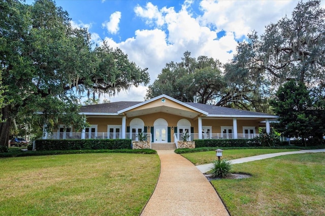 view of front facade featuring stucco siding, a front lawn, covered porch, and french doors