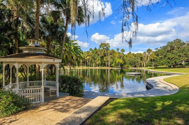 view of dock featuring a water view, a lawn, and a gazebo