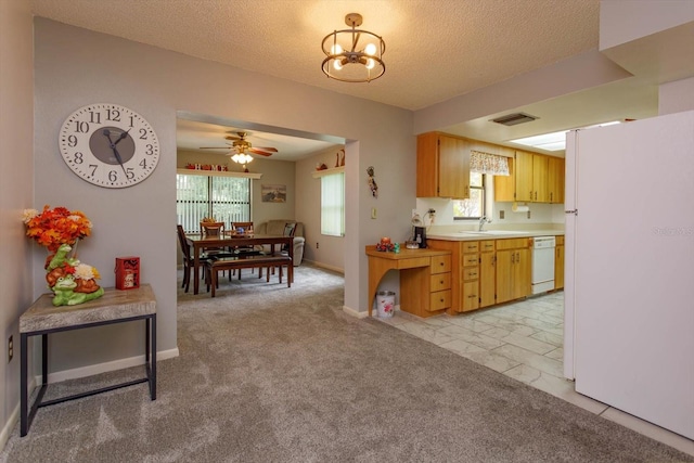 kitchen with ceiling fan with notable chandelier, a textured ceiling, white appliances, light colored carpet, and sink