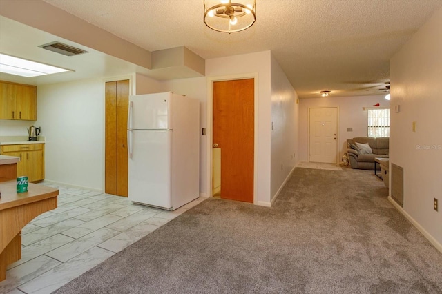 kitchen featuring a textured ceiling, white fridge, ceiling fan, and light colored carpet