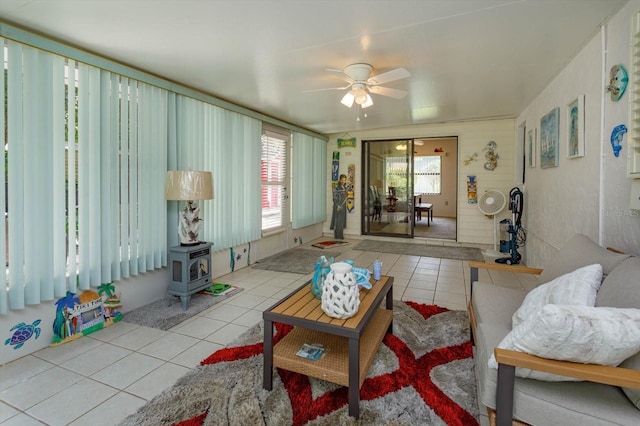 tiled living room with a wood stove and ceiling fan