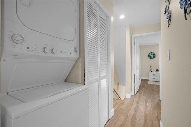 laundry area with stacked washing maching and dryer and light hardwood / wood-style floors