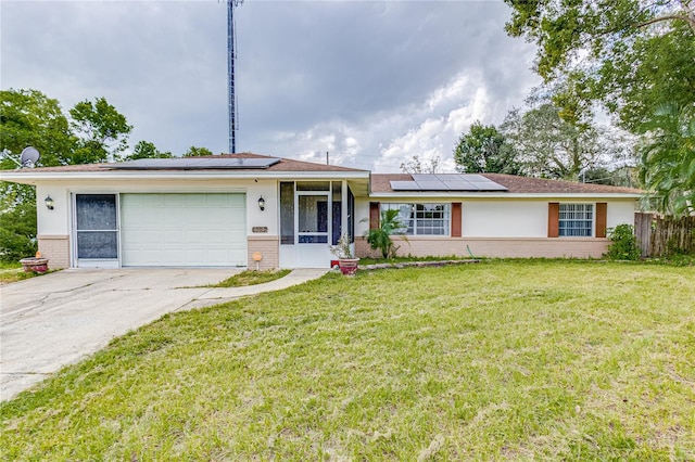 ranch-style house with a front yard, solar panels, and a garage