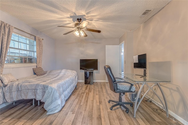 bedroom with a textured ceiling, light hardwood / wood-style floors, and ceiling fan