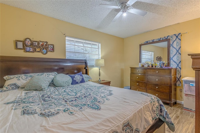 bedroom featuring ceiling fan, a textured ceiling, and light hardwood / wood-style flooring