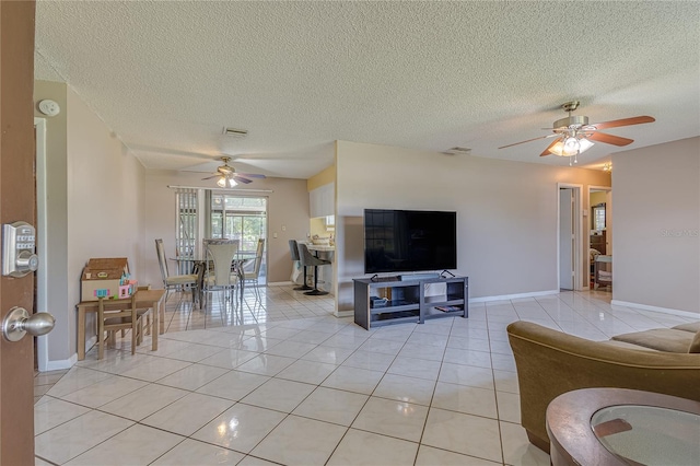 living room with a textured ceiling, light tile patterned floors, and ceiling fan