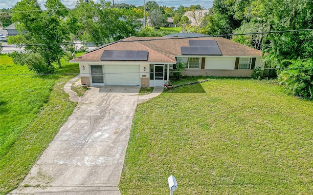ranch-style home with a front yard, solar panels, and a garage
