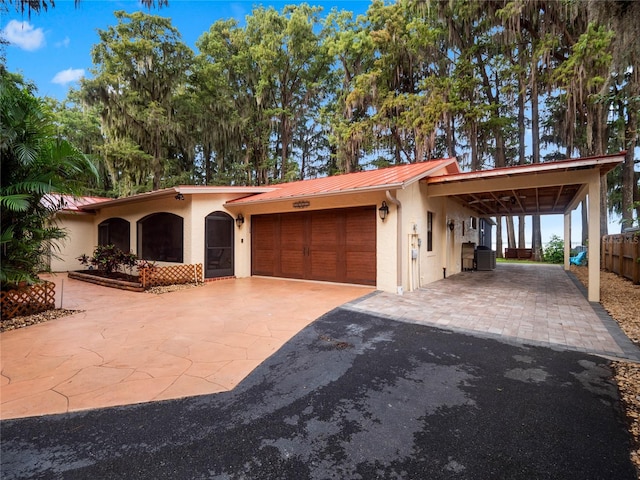 view of front of house with a garage, concrete driveway, metal roof, and stucco siding