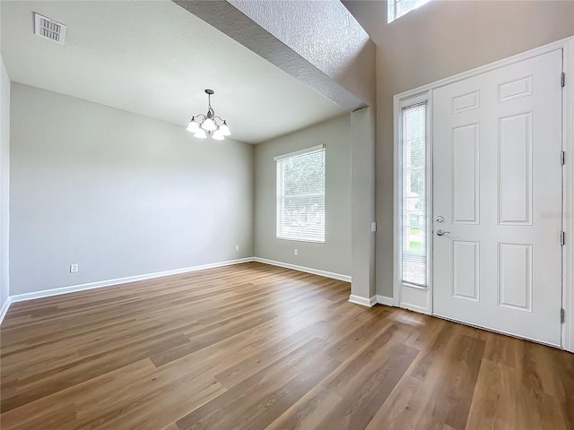 foyer with a wealth of natural light, wood-type flooring, and a chandelier