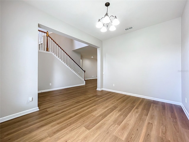 spare room featuring light wood-type flooring and a notable chandelier