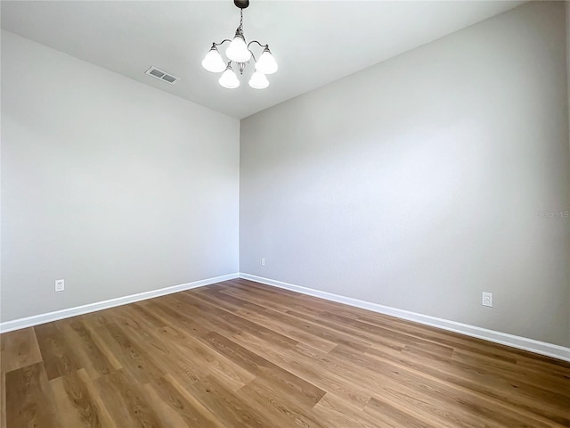 unfurnished room featuring an inviting chandelier and light hardwood / wood-style floors