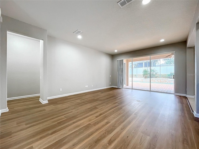 empty room with hardwood / wood-style floors and a textured ceiling