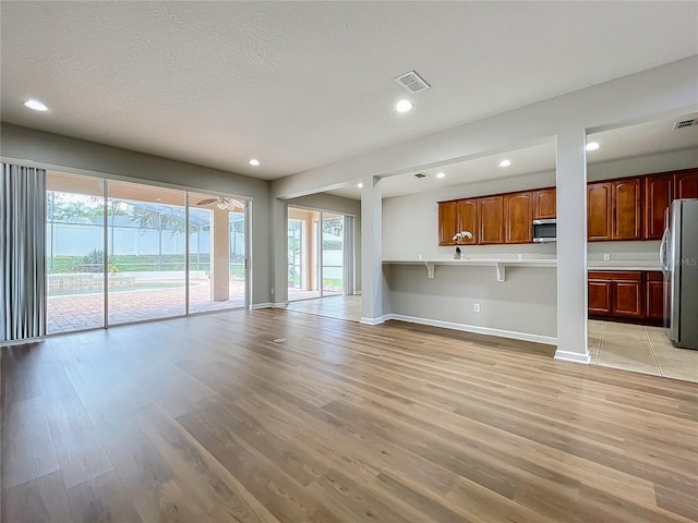 unfurnished living room with a textured ceiling and light hardwood / wood-style floors