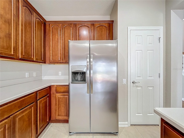 kitchen featuring a textured ceiling, light tile patterned flooring, and stainless steel refrigerator with ice dispenser