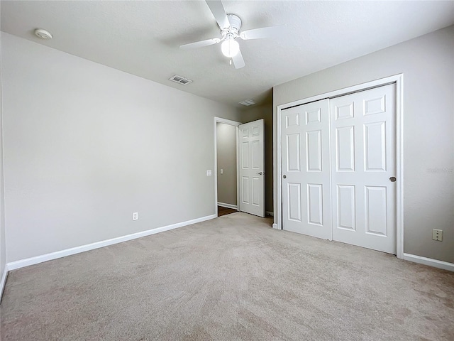 unfurnished bedroom featuring a textured ceiling, light colored carpet, ceiling fan, and a closet