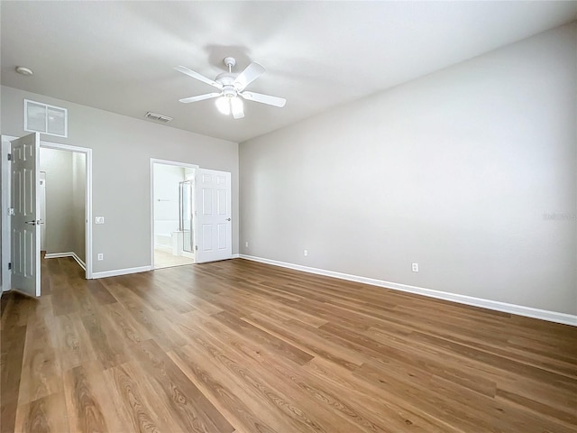 unfurnished bedroom with a walk in closet, ceiling fan, ensuite bathroom, and light hardwood / wood-style flooring