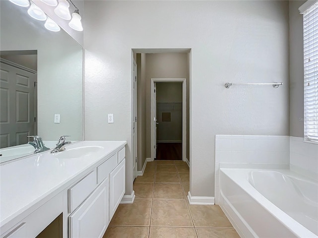 bathroom with tile patterned floors, a bathtub, a wealth of natural light, and vanity