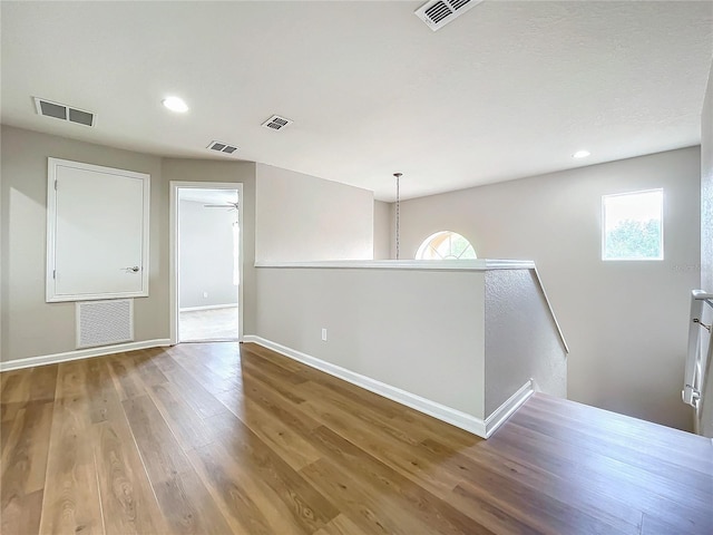 empty room featuring ceiling fan with notable chandelier and hardwood / wood-style flooring