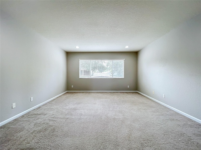 empty room with light carpet and a textured ceiling