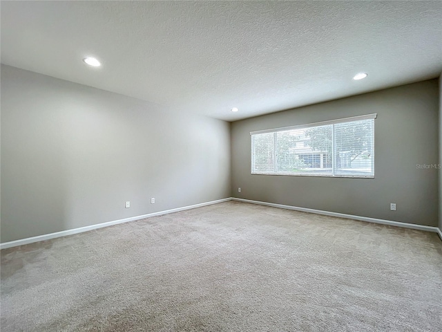 spare room with a textured ceiling and light colored carpet