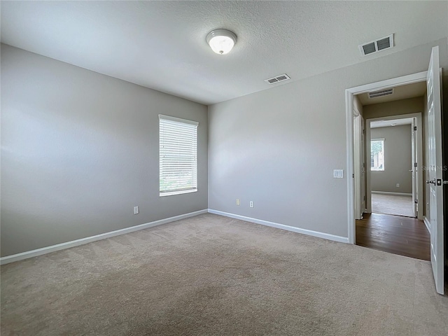 carpeted spare room featuring a textured ceiling