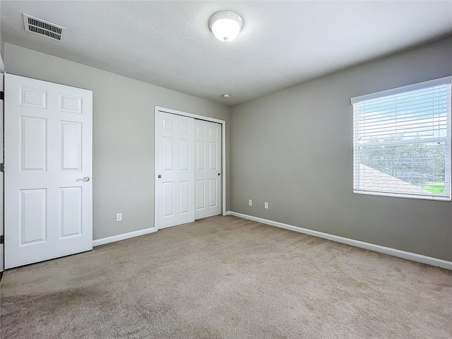 unfurnished bedroom with a closet and light colored carpet