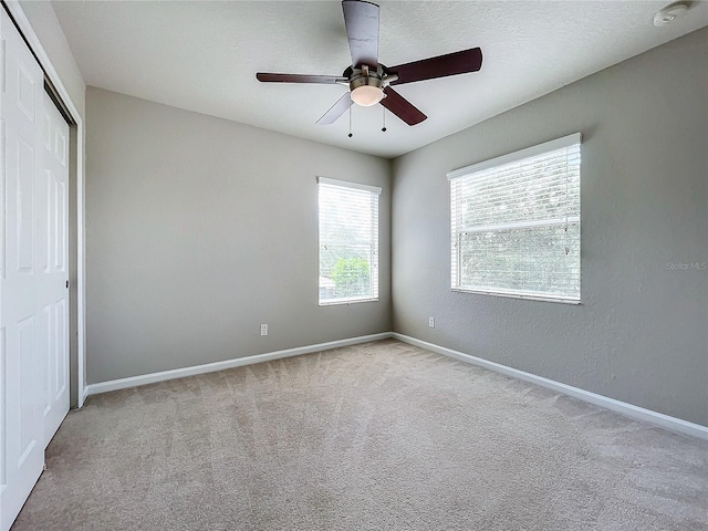 unfurnished bedroom featuring light carpet, a textured ceiling, ceiling fan, and a closet