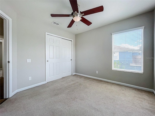 unfurnished bedroom with light carpet, ceiling fan, and a closet