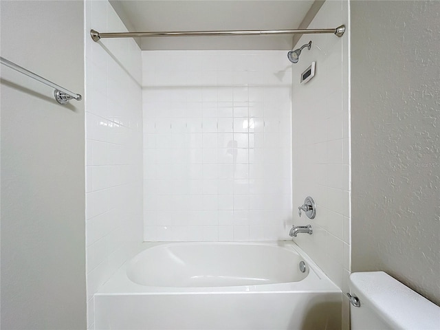 bathroom featuring tiled shower / bath and toilet