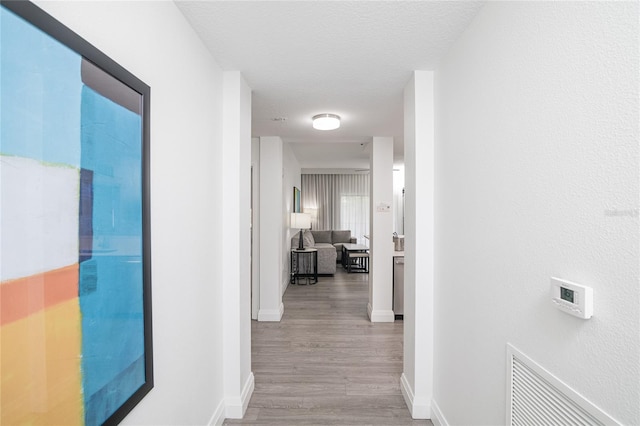 hall featuring a textured ceiling and light hardwood / wood-style flooring