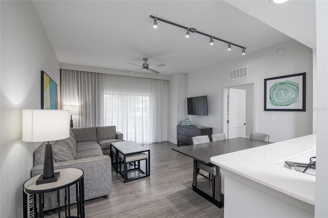 living room with track lighting, hardwood / wood-style flooring, and ceiling fan