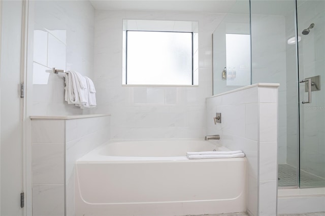 bathroom featuring tile walls and independent shower and bath