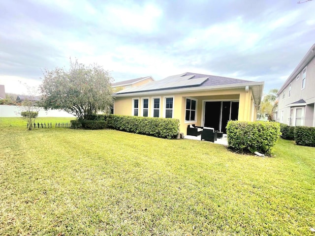 back of property with solar panels, outdoor lounge area, a yard, and stucco siding