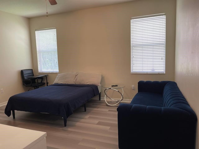 bedroom with a ceiling fan, baseboards, and light wood-type flooring