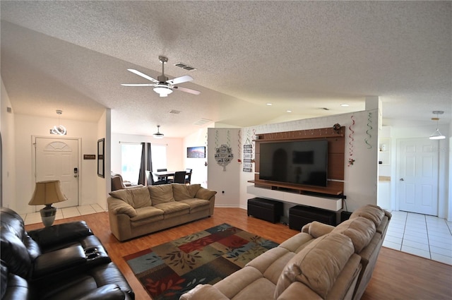 living room with lofted ceiling, ceiling fan, light hardwood / wood-style floors, and a textured ceiling