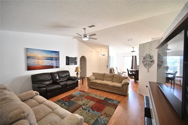 living room featuring lofted ceiling, ceiling fan, hardwood / wood-style flooring, and a textured ceiling