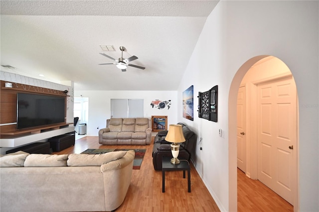 living room featuring ceiling fan, light hardwood / wood-style floors, a textured ceiling, and vaulted ceiling