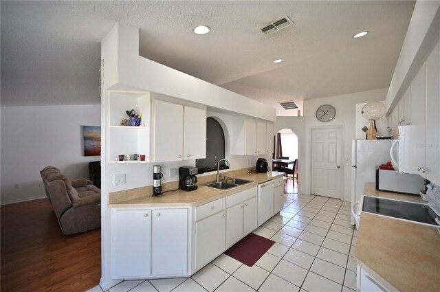 kitchen with white appliances, white cabinetry, light hardwood / wood-style flooring, a textured ceiling, and sink