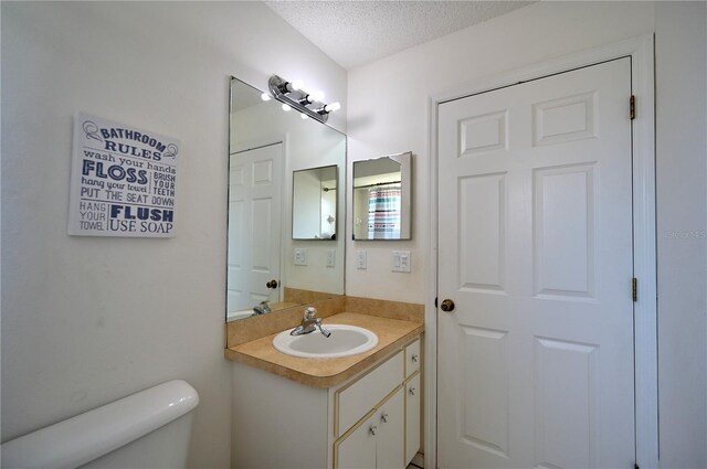 bathroom featuring vanity, toilet, and a textured ceiling