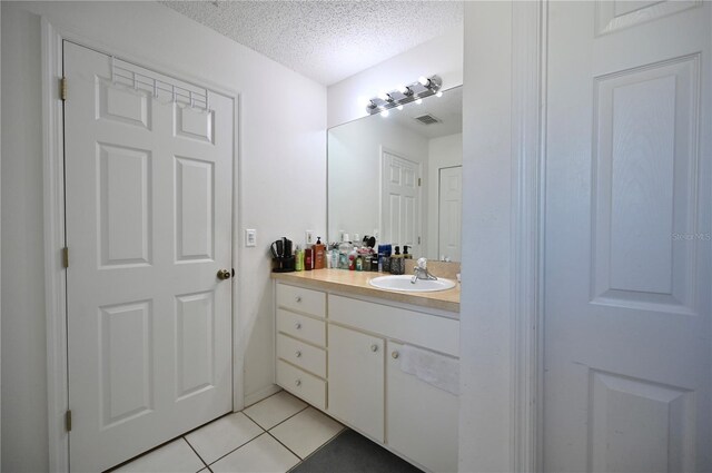 bathroom with tile patterned flooring, vanity, and a textured ceiling